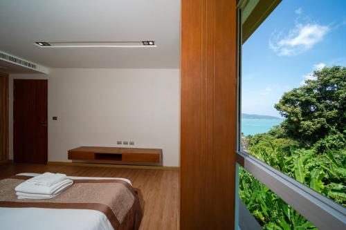 a bedroom with a bed and a large window at Patong Kalim Unparalleled Sea View B&B Resort in Patong Beach