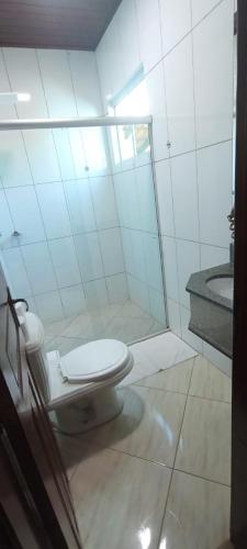 a white bathroom with a toilet and a sink at Pousada Casa Rosa in Alto Paraíso de Goiás