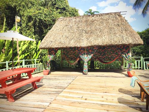 a pavilion with a thatch roof with a bench and a table at Maya Mountain Lodge in San Ignacio