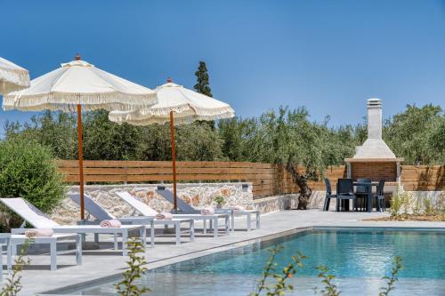 a swimming pool with chairs and umbrellas next to a pool at Edward Stone Villa in Tragaki