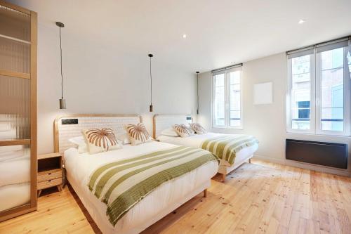 deux lits dans une chambre avec des murs et des fenêtres blancs dans l'établissement Charming Apt - 2BD-10P - Buttes aux Cailles, à Paris