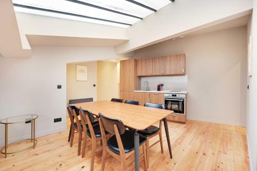 une cuisine et une salle à manger avec une table et des chaises en bois dans l'établissement Charming Apt - 2BD-10P - Buttes aux Cailles, à Paris