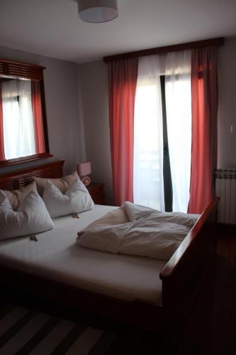 a bedroom with a large bed with two windows at Intermezzo Vuk in Banja Luka
