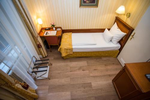 a small room with a bed and a desk at Pension Opera Suites I Self Check In in Vienna