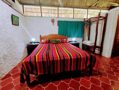 a bedroom with a bed with a colorful striped comforter at Maya Mountain Lodge in San Ignacio
