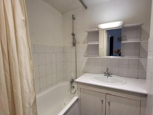 La salle de bains est pourvue d'un lavabo, d'une baignoire et d'un rideau de douche. dans l'établissement T2 avec balcon exposé sud à 500m des pistes - FR-1-449-167, à Tignes