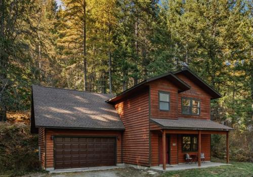 a log house with a garage in the woods at Family Home - Sandpointschweitzer in Sandpoint