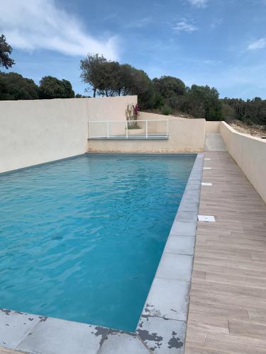 - une piscine d'eau bleue à côté d'un mur dans l'établissement mini villa duplex Bonifacio 70m2, à Bonifacio