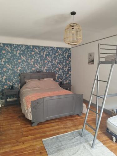 une chambre avec un lit avec du papier peint fleuri et une échelle dans l'établissement Jolie maison de bourg tout équipée 10km d'Ambert, à Saint-Amant-Roche-Savine