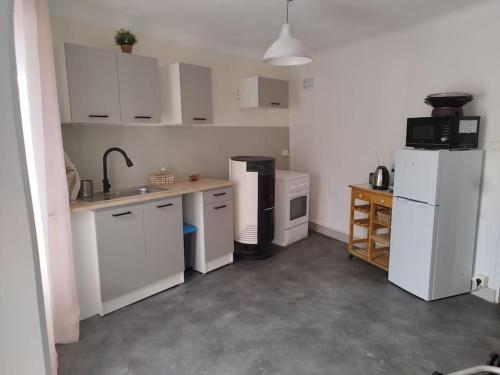 a kitchen with white cabinets and a white refrigerator at Jolie maison de bourg tout équipée 10km d'Ambert in Saint-Amant-Roche-Savine