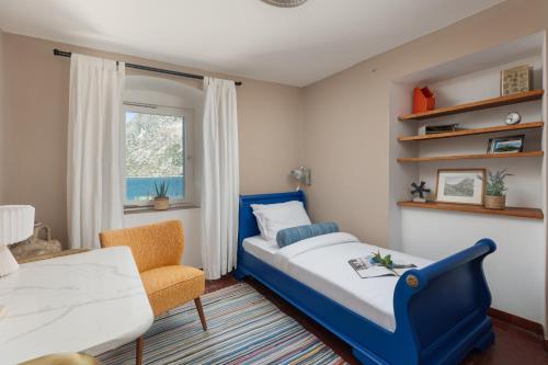 a bedroom with a bed and a chair and a window at Villa Blue Dream in Dobrota