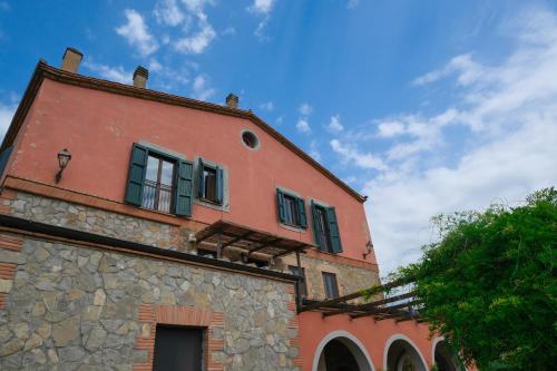 a red brick building with green windows on it at Casale Beatrice degli Ulivi in Orvieto