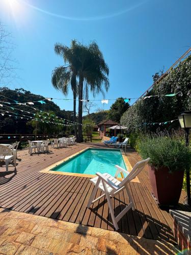 a swimming pool with a deck and chairs and a palm tree at Pousada Shangri-lá in Cunha