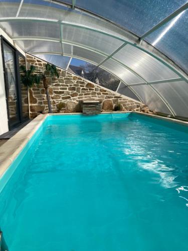 une grande piscine d'eau bleue dans un bâtiment dans l'établissement maison avec piscine couverte, à Louannec