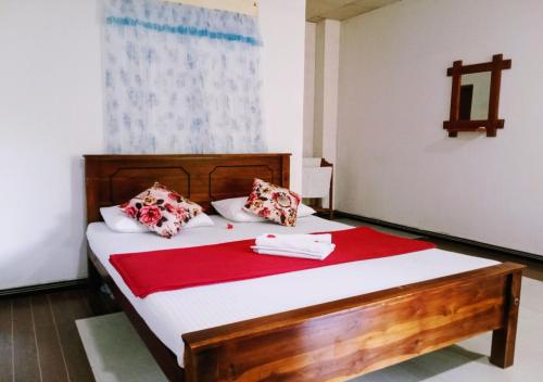 a bedroom with a wooden bed with red and white pillows at Jm Resort in Dambulla