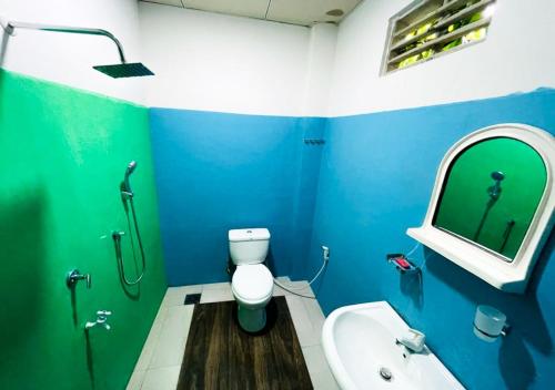 a blue bathroom with a toilet and a sink at Jm Resort in Dambulla