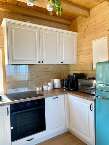 a kitchen with white cabinets and a black appliance at Rajski Zakątek - jeden domek na działce z gorącą balią i mini ZOO in Kamionka Wielka
