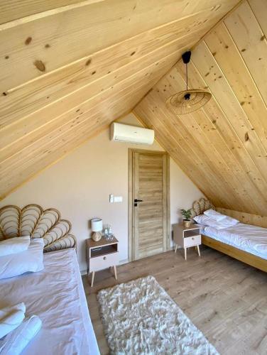 a bedroom with two beds and a wooden ceiling at Rajski Zakątek - jeden domek na działce z gorącą balią i mini ZOO in Kamionka Wielka