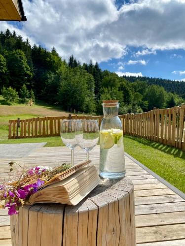 two wine glasses and a bottle of water on a wooden table at Rajski Zakątek - jeden domek na działce z gorącą balią i mini ZOO in Kamionka Wielka