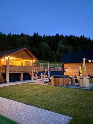 a log cabin with a deck and a playground at Rajski Zakątek - jeden domek na działce z gorącą balią i mini ZOO in Kamionka Wielka