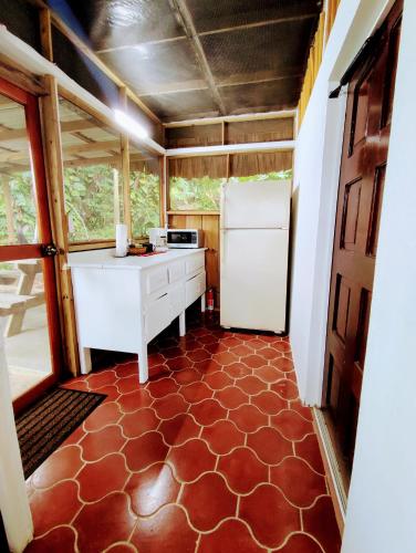 a kitchen with a white refrigerator and a red floor at Maya Mountain Lodge in San Ignacio