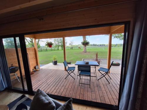 une terrasse en bois avec une table et des chaises. dans l'établissement Le Chalet de la Licorne, à Sérent