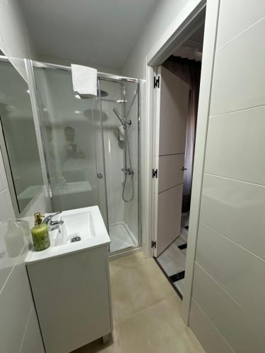 a white bathroom with a shower and a sink at Hostal Arrate in Madrid