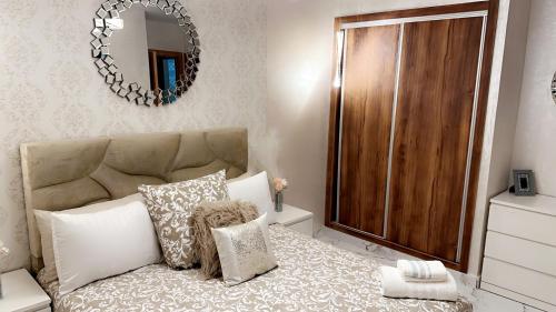 a bedroom with a bed with a mirror on the wall at Superbe appartement de luxe- proche de la mer - Dahomey city - Bouznika in Bouznika