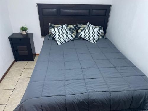 a bed with blue sheets and pillows in a room at Alojamiento Puente Alto in Santiago