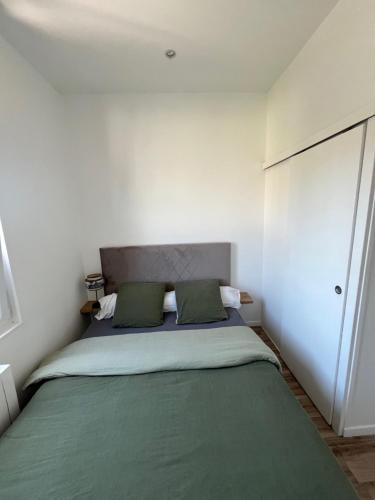 a bedroom with a large bed with green sheets at Le Compiègnois in Compiègne