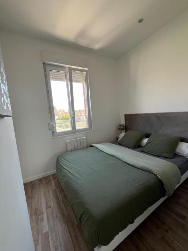 a bedroom with a large bed and two windows at Le Compiègnois in Compiègne