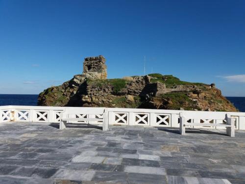 a white fence next to the ocean with a castle at Semi's House in Batsi