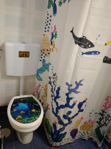 a bathroom with a toilet with a fish shower curtain at Semi's House in Batsi