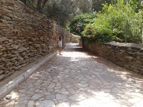 a woman standing next to a stone wall at Semi's House in Batsi