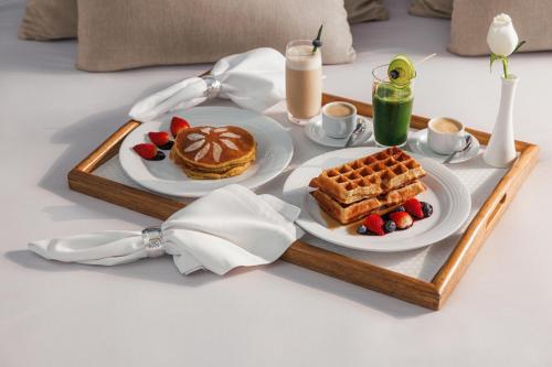 - un plateau de petit-déjeuner avec des gaufres et des fruits sur une table dans l'établissement BON Hotel at VidantaWorld Nuevo Vallarta, à Nuevo Vallarta