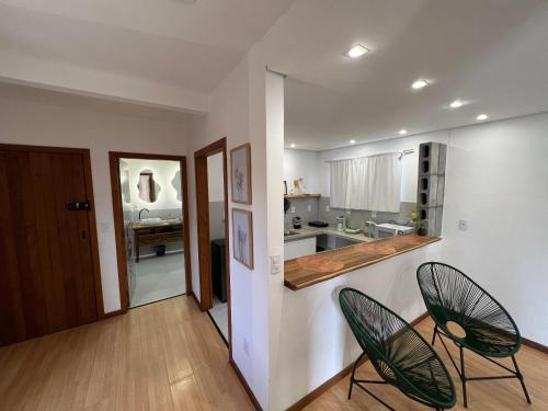 a living room with two chairs and a kitchen at Studios Aromas do Campeche - Floripa in Florianópolis