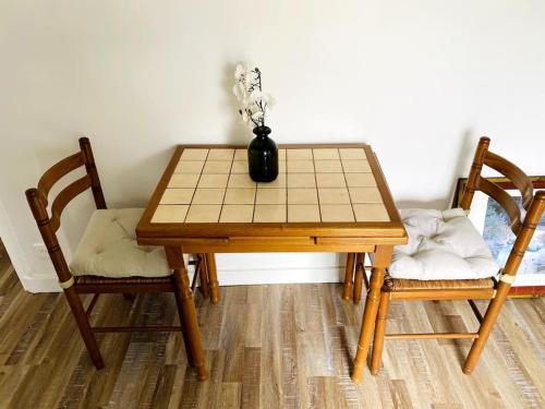 - une table en bois avec 2 chaises et un vase dans l'établissement Maj Appart Iéna - Paris 16, à Paris