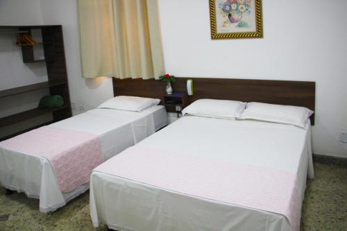 two beds in a hotel room with white sheets at Hotel Marajoara in Belém