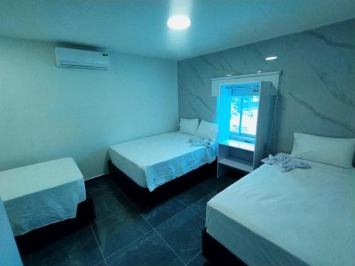 a hotel room with two beds and a window at Hotel Mall plaza in Santa Marta