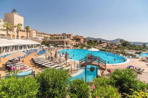 une grande piscine avec des chaises et des parasols dans un complexe dans l'établissement Résidence le Village de Cap Esterel - maeva Home - Appartement cosy 2 pièces 4 personnes - Prestige - super Home MAE-2121, à Saint-Raphaël