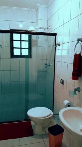 een badkamer met een douche, een toilet en een wastafel bij Pousada Beira Mar in Mongaguá