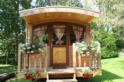 a wooden gazebo with flowers in a yard at Les roulottes a Sandie in Thionville