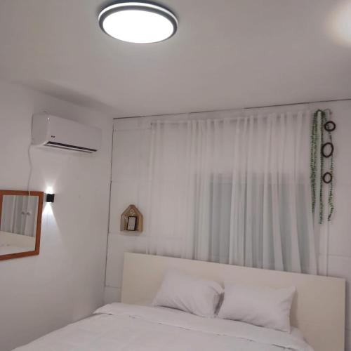 a bedroom with a white bed and a window at בין העצים in Petaẖ Tiqwa