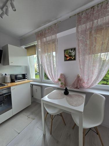 a kitchen with a white table and chairs and a window at Dworcowa przy basenie in Olsztyn