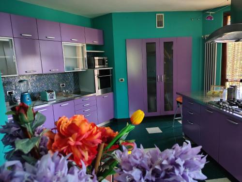 a purple and green kitchen with purple cabinets and flowers at FairiesApt in Casalmoro
