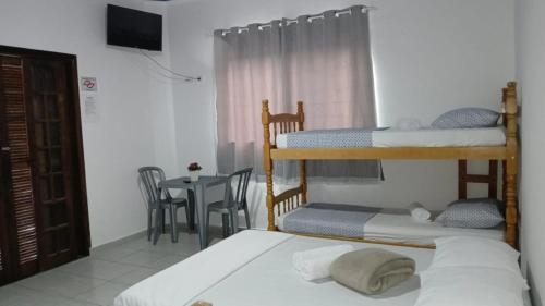 een slaapkamer met twee stapelbedden en een tafel bij Pousada Beira Mar in Mongaguá