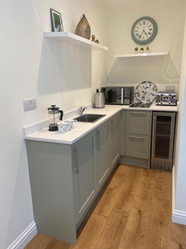 a kitchen with a sink and a clock on the wall at Newton House Apartment, Newton Burgoland in Heather