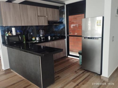 a kitchen with a stainless steel refrigerator and wooden floors at Apartamento en Cartago Valle - Hospedaje in Cartago