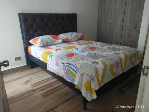 a bed with a colorful comforter and two pillows at Apartamento en Cartago Valle - Hospedaje in Cartago