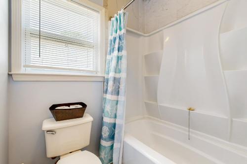 a bathroom with a toilet and a tub and a window at Shady Retreat in Tybee Island